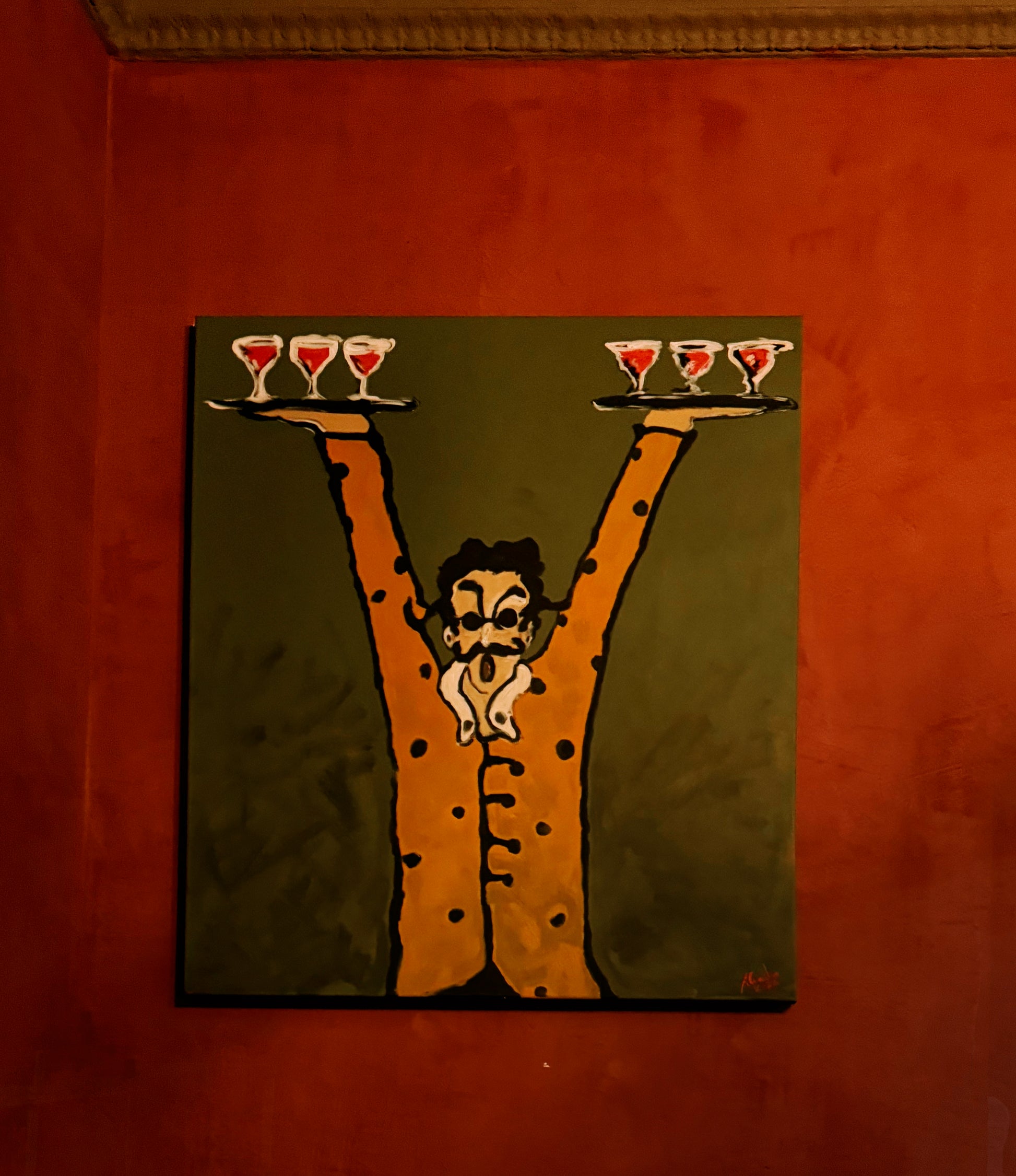 Painting of a man with a mustache holding three cocktail glasses on a red wall.