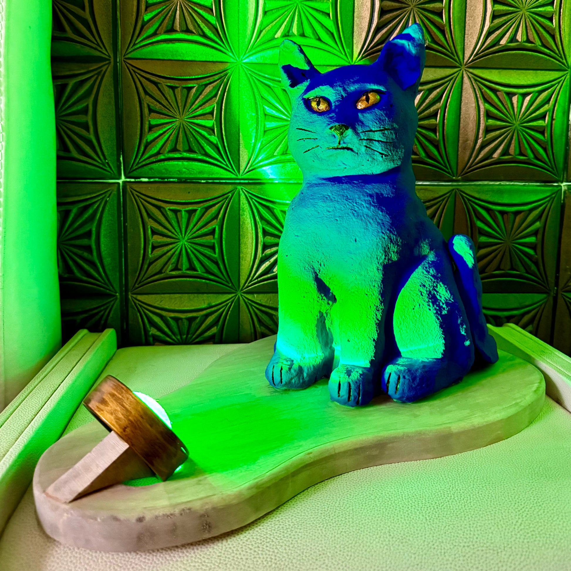 Blue cat figurine on a green platform with a green tiled wall background
