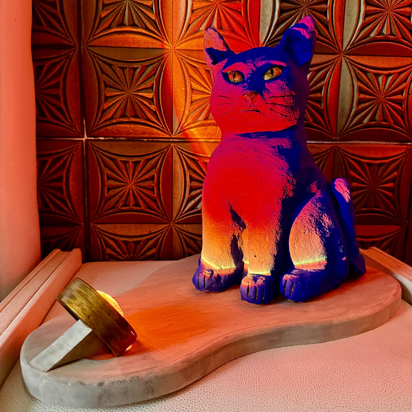 Cat-shaped lamp with a warm glow on a wooden surface against a textured red wall.