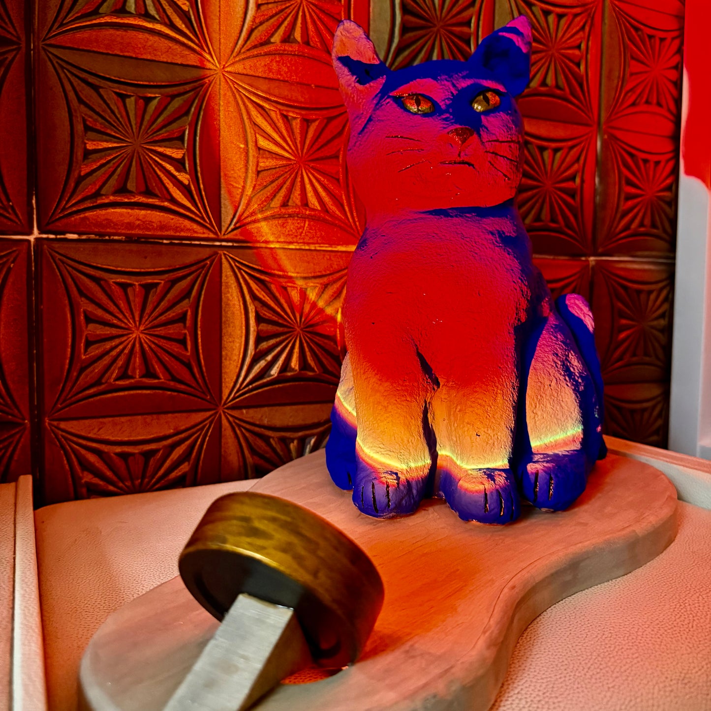 Colorful cat-shaped object on a wooden surface with a patterned wall in the background