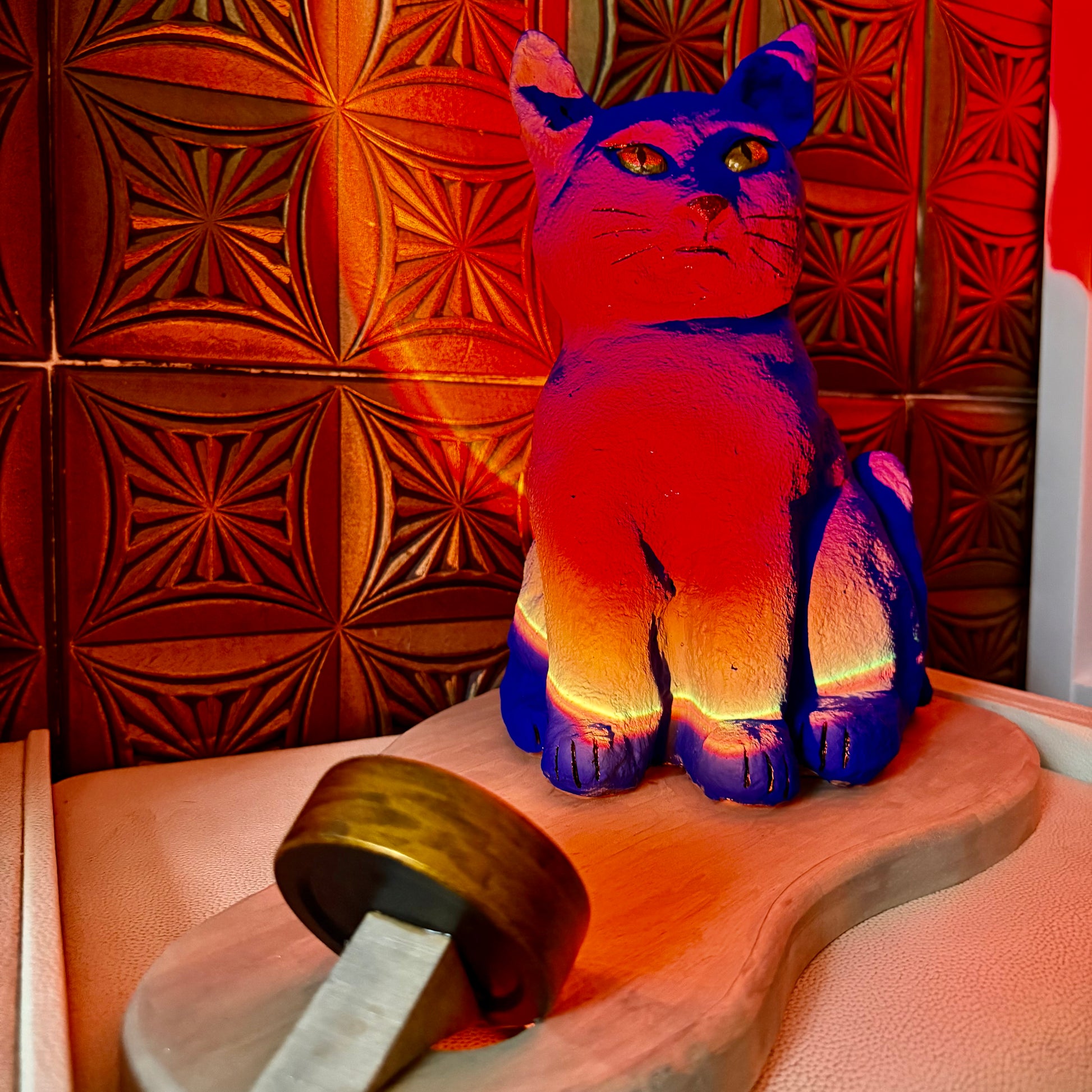 Colorful cat-shaped object on a wooden surface with a patterned wall in the background