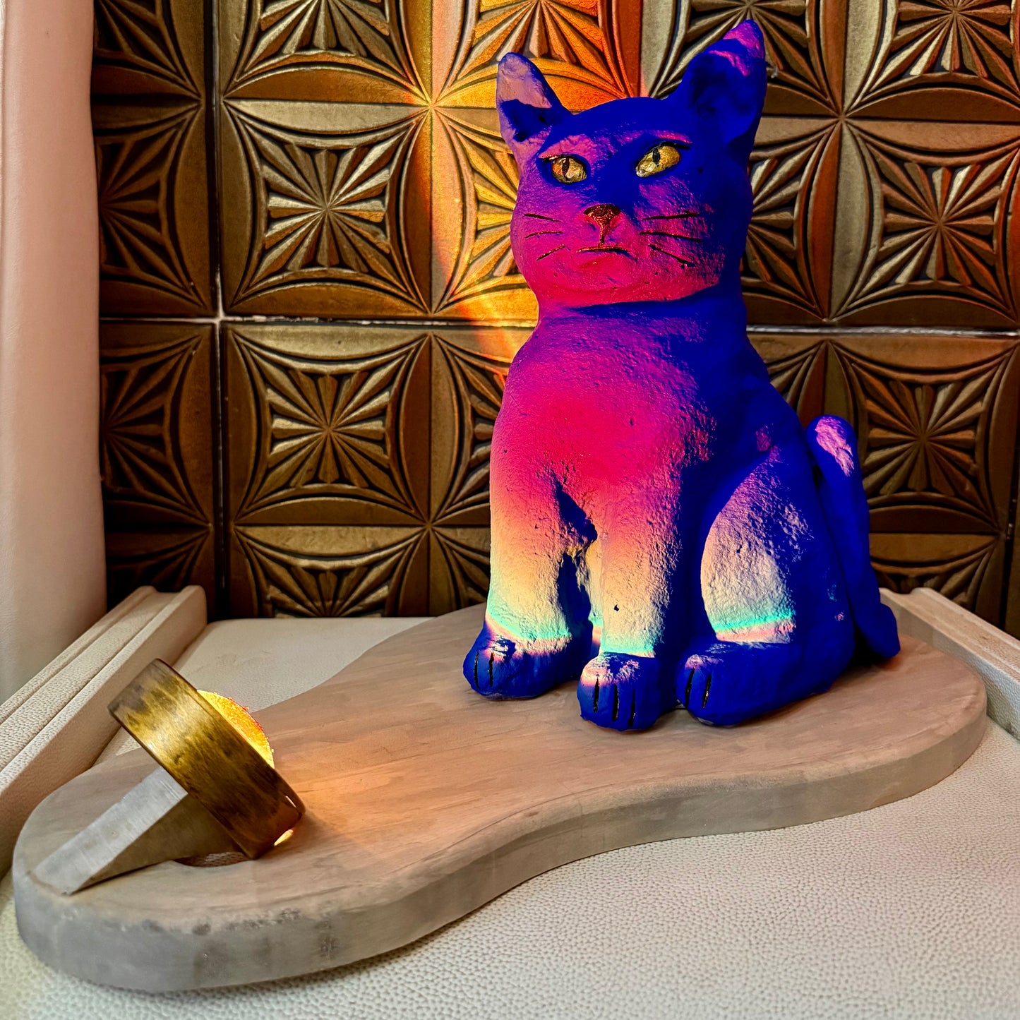 Colorful cat-shaped lamp on a wooden platform with a patterned wall in the background