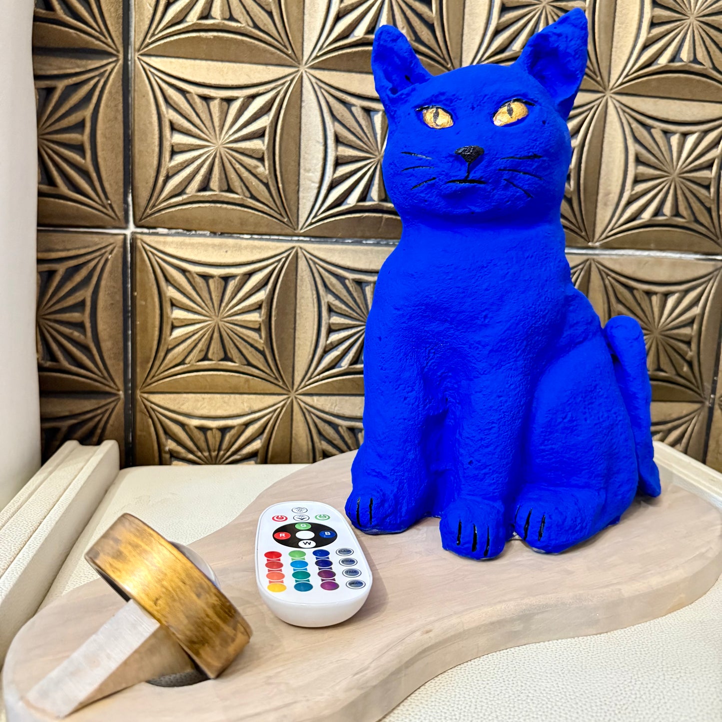 Blue cat-shaped object on a wooden surface with a decorative tile wall in the background