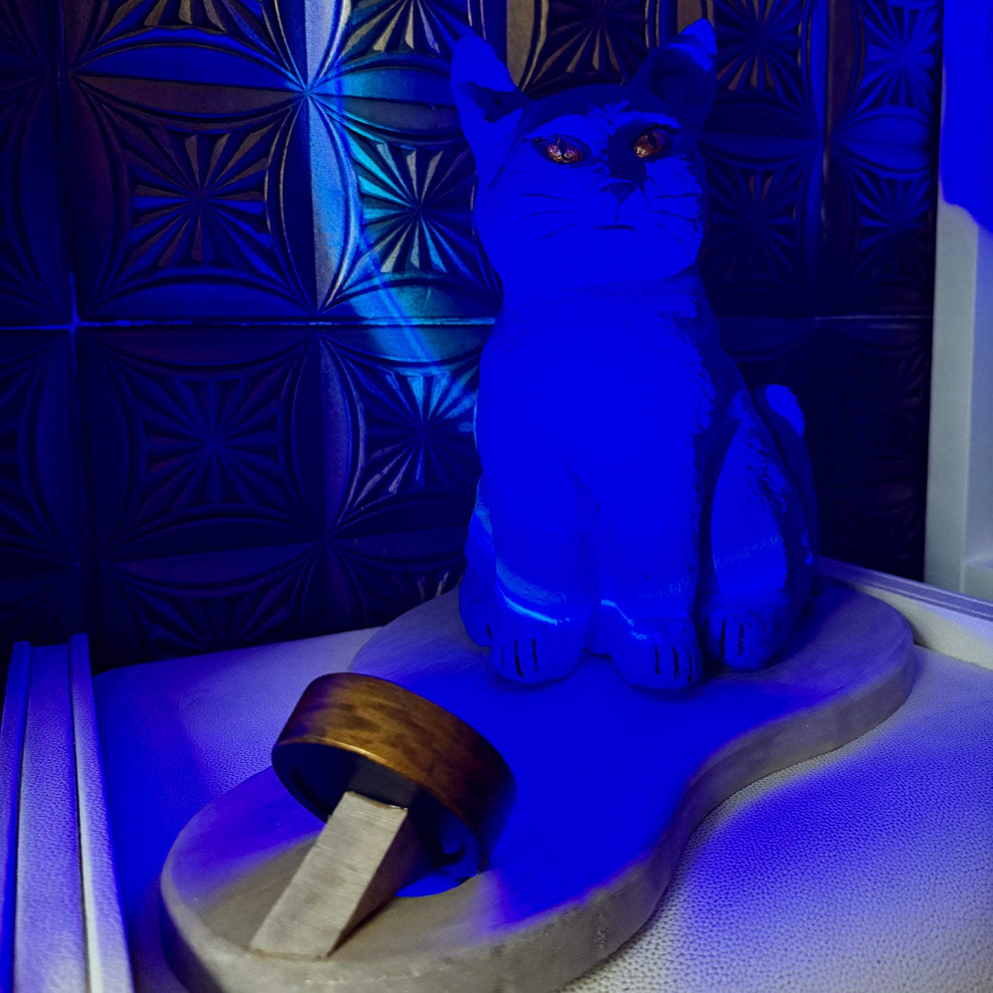 Blue cat-shaped object on a textured surface with a patterned wall in the background