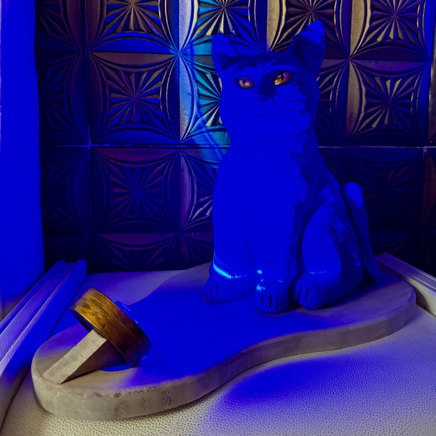 Blue cat-shaped lamp on a textured surface with a patterned wall in the background