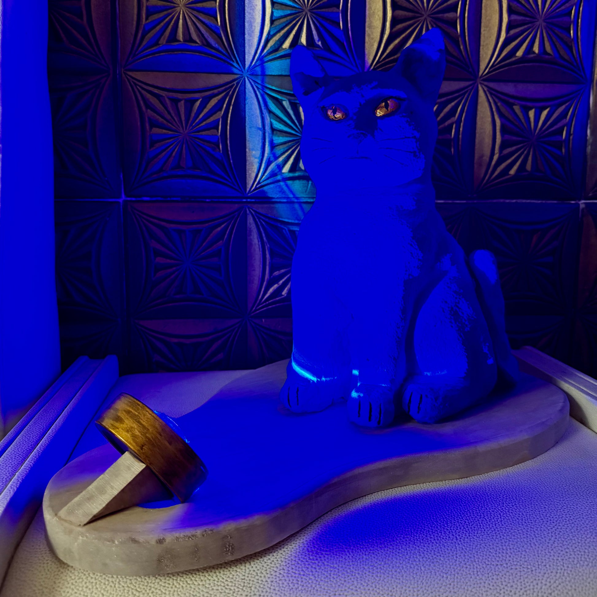 Blue cat-shaped lamp on a textured surface with a patterned wall in the background