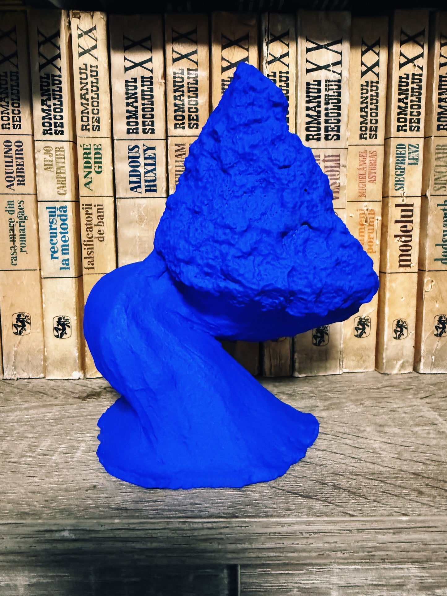 Blue sculpture on a wooden surface with a background of stacked boxes.