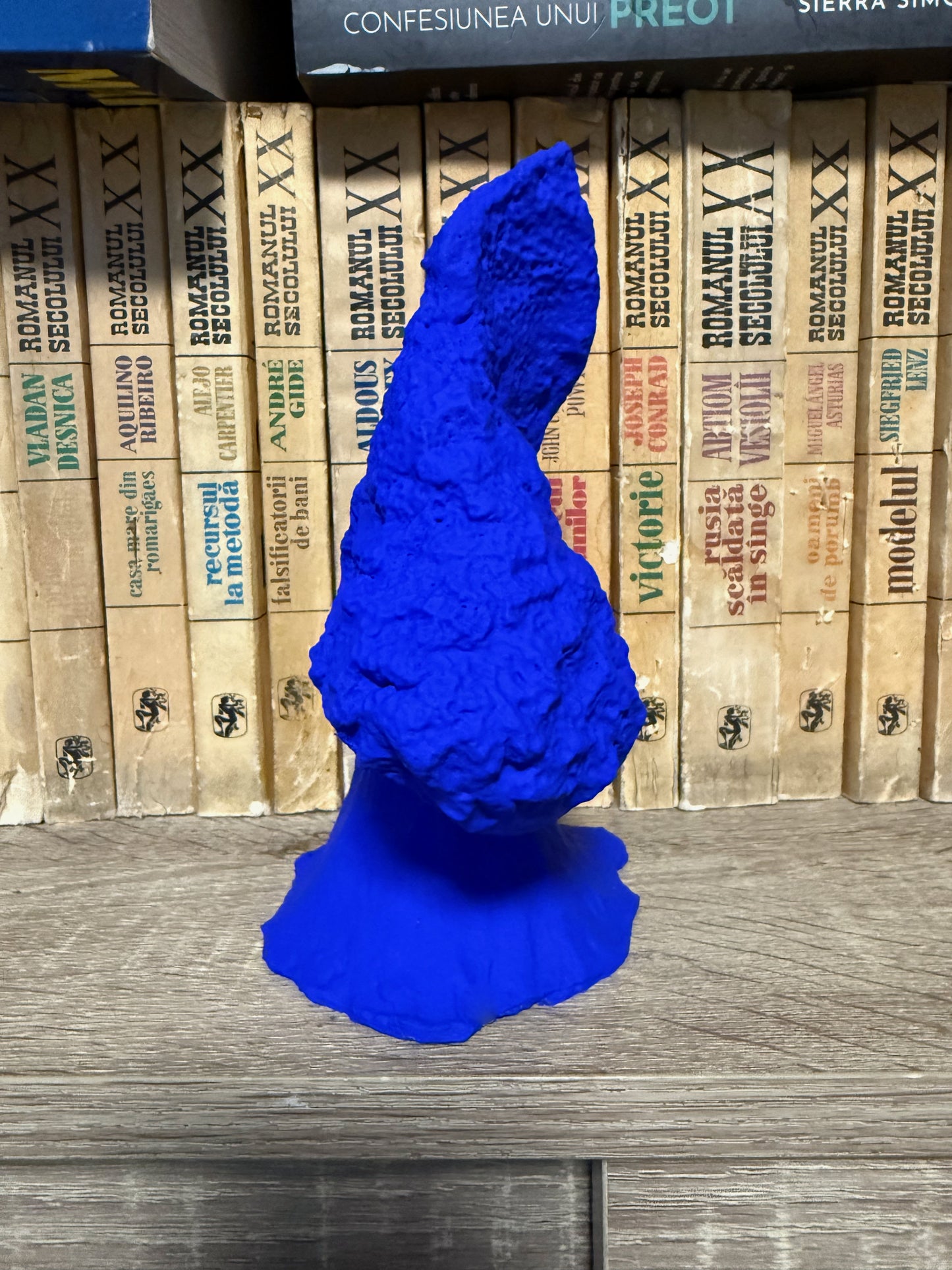 Blue 3D-printed object on a wooden surface with stacked books in the background