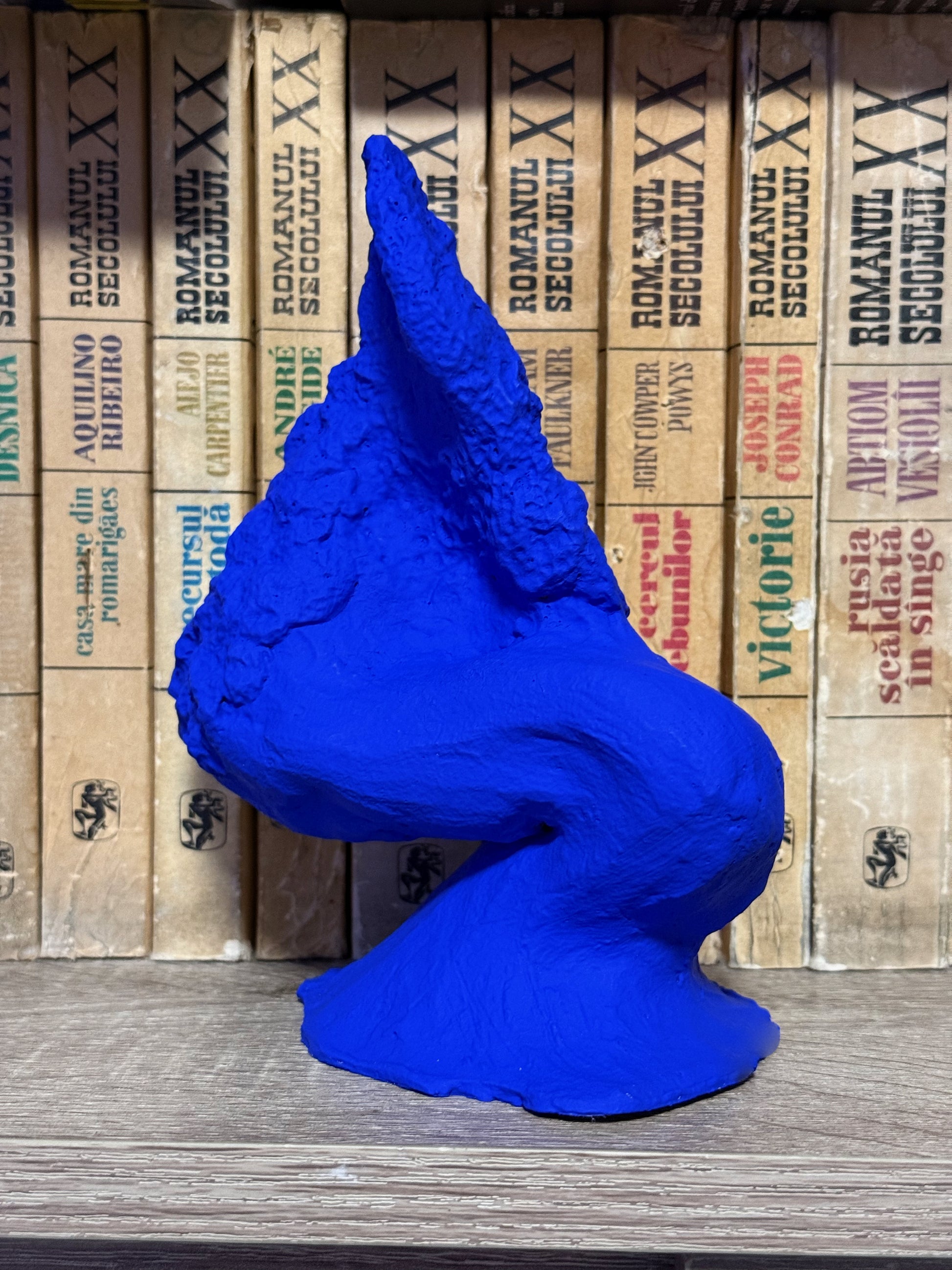 Blue sculpture on a wooden surface with vintage cardboard boxes in the background