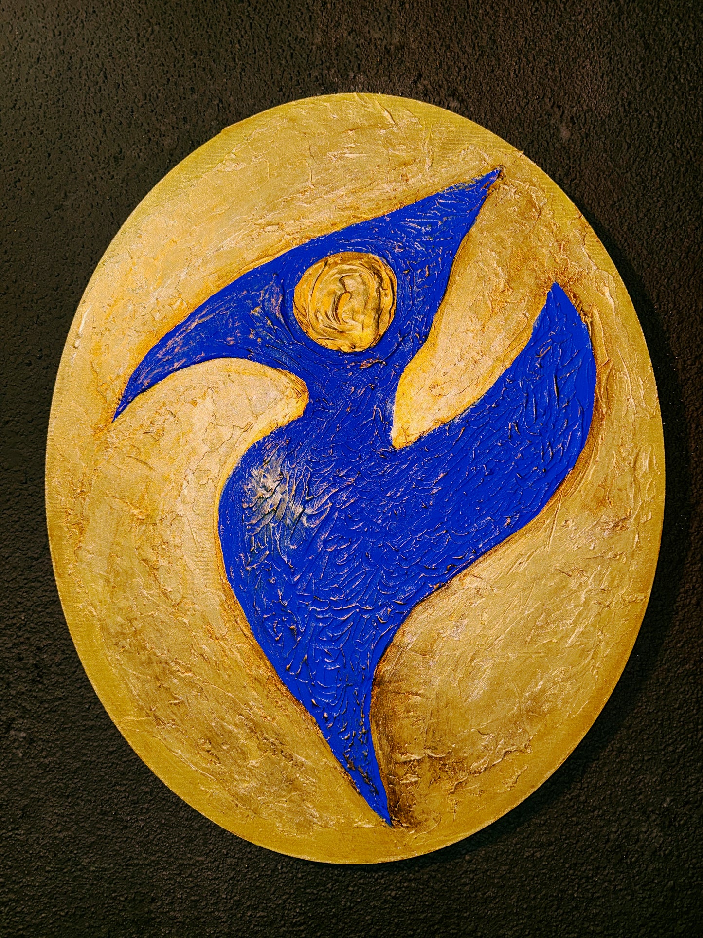 Decorative stone with blue and gold design on a dark background