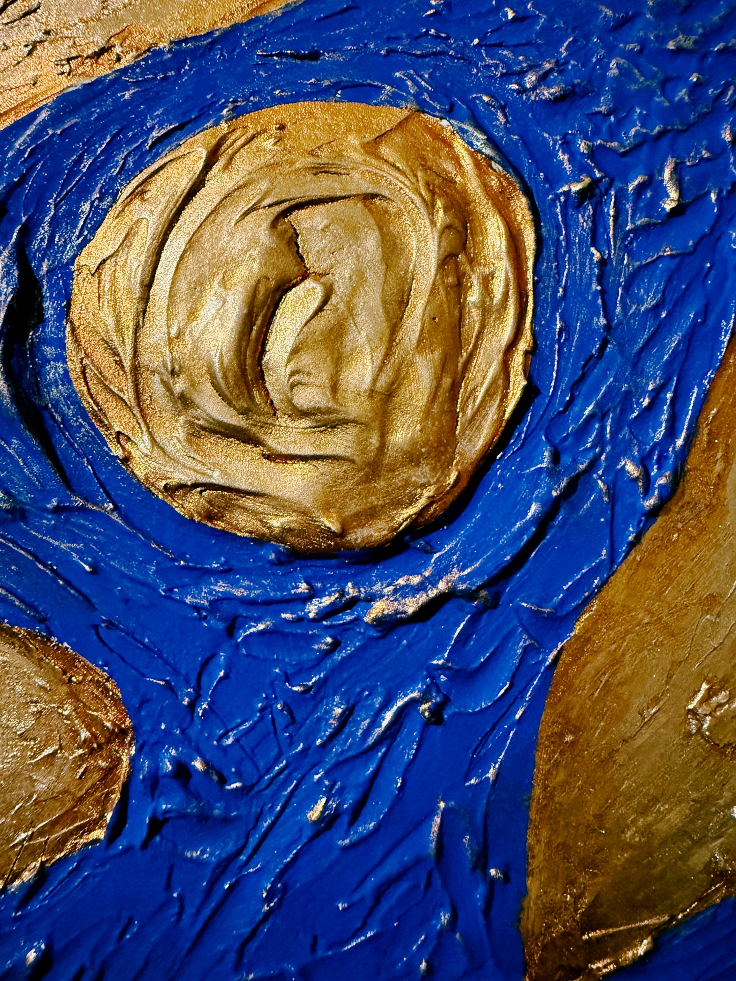 Close-up of a textured painting with blue and gold colors