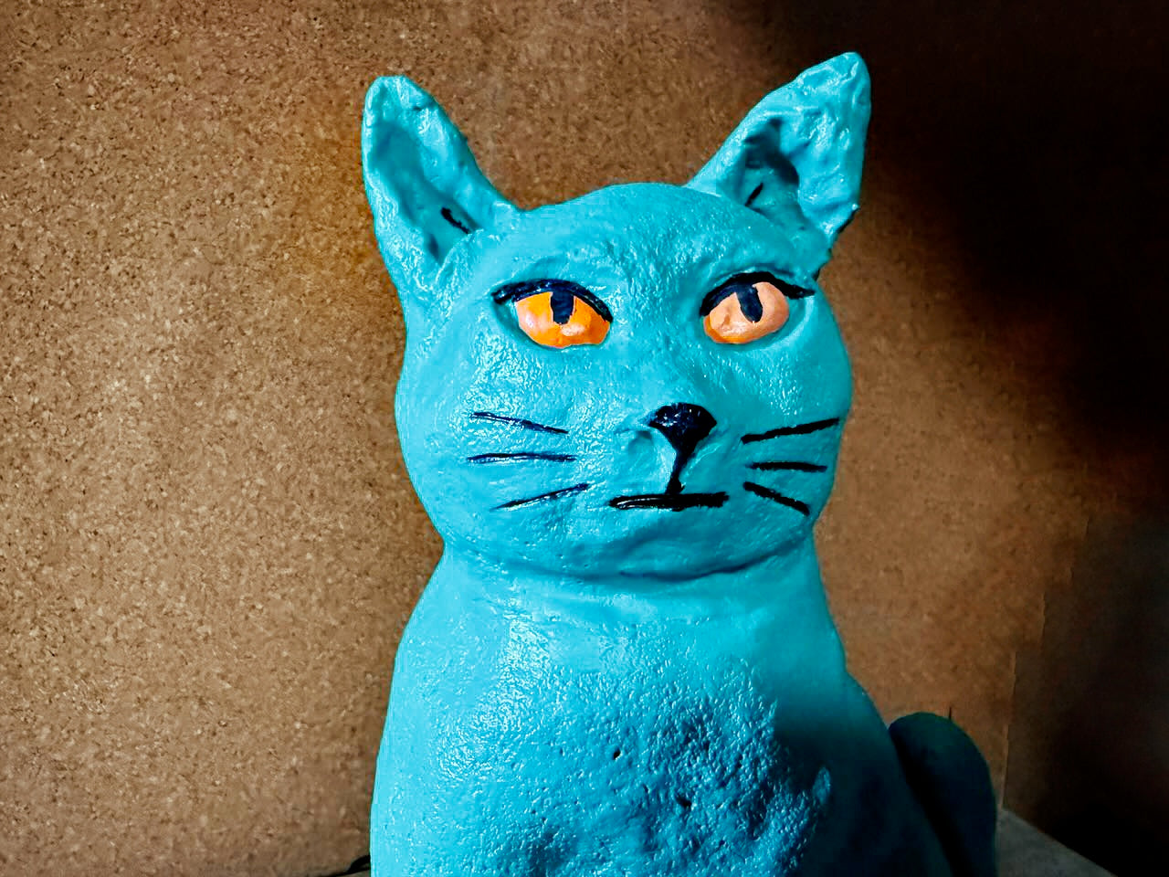 Blue cat figurine with orange eyes on a brown background
