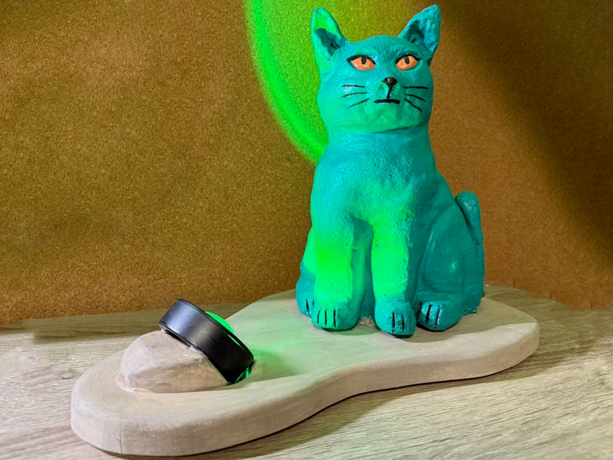 Green cat-shaped object on a wooden base with a green light in the background
