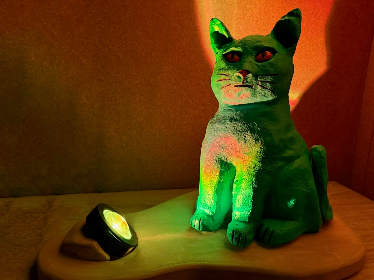 Green cat-shaped lamp on a wooden base with a warm glow.