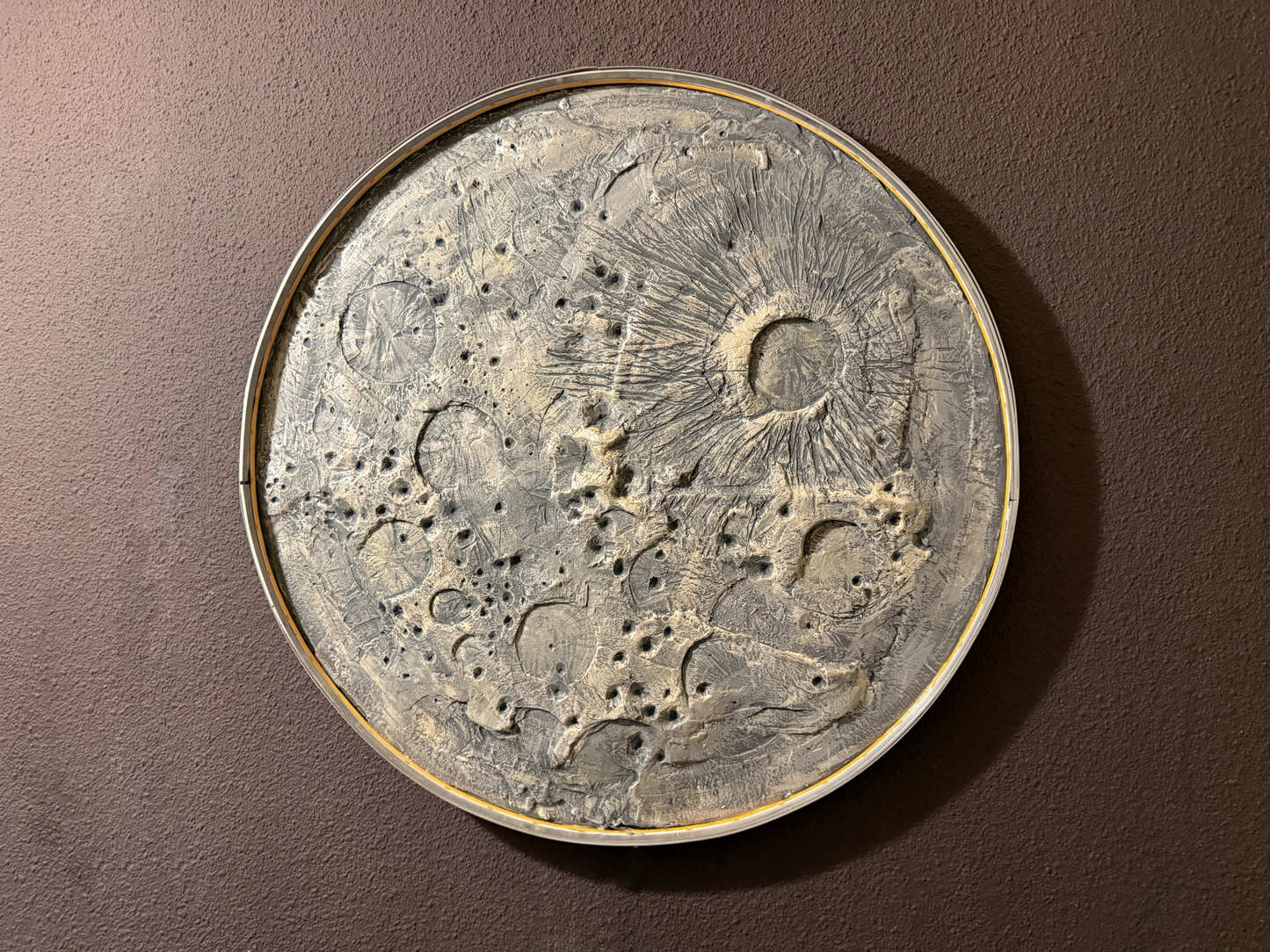 Decorative circular wall art with celestial design on a brown background