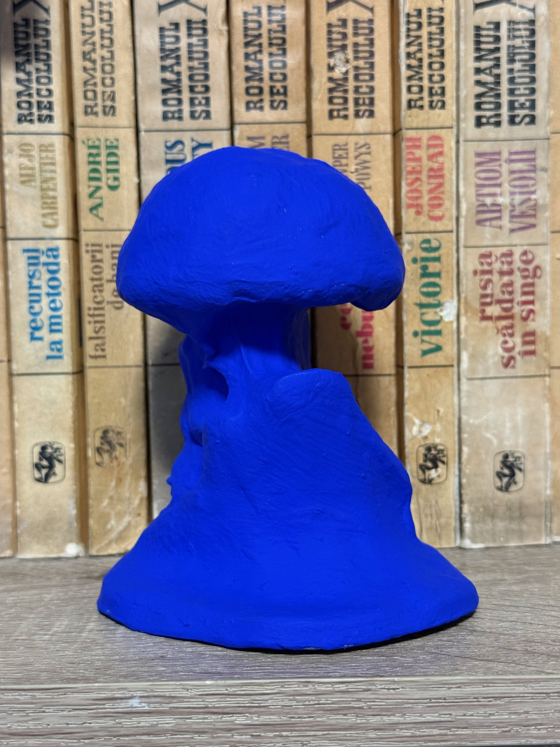 Blue mushroom-shaped object on a wooden surface with vintage cardboard boxes in the background