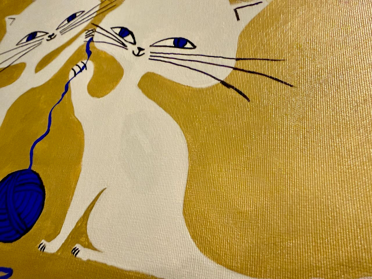 Illustration of a cat playing with a blue yarn ball on a gold background