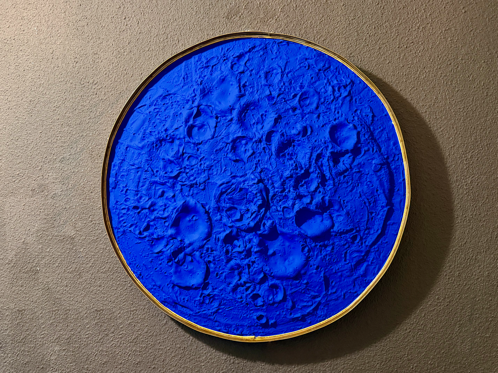 Blue textured circular artwork on a beige wall