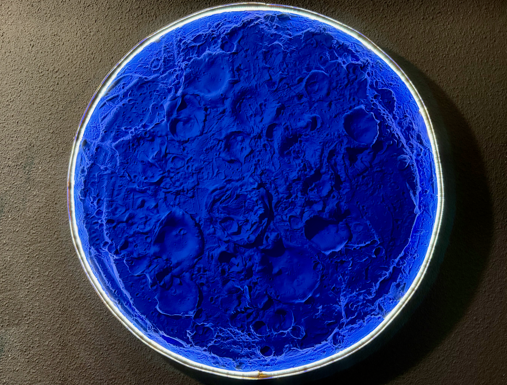 Blue powder in a round container on a brown background