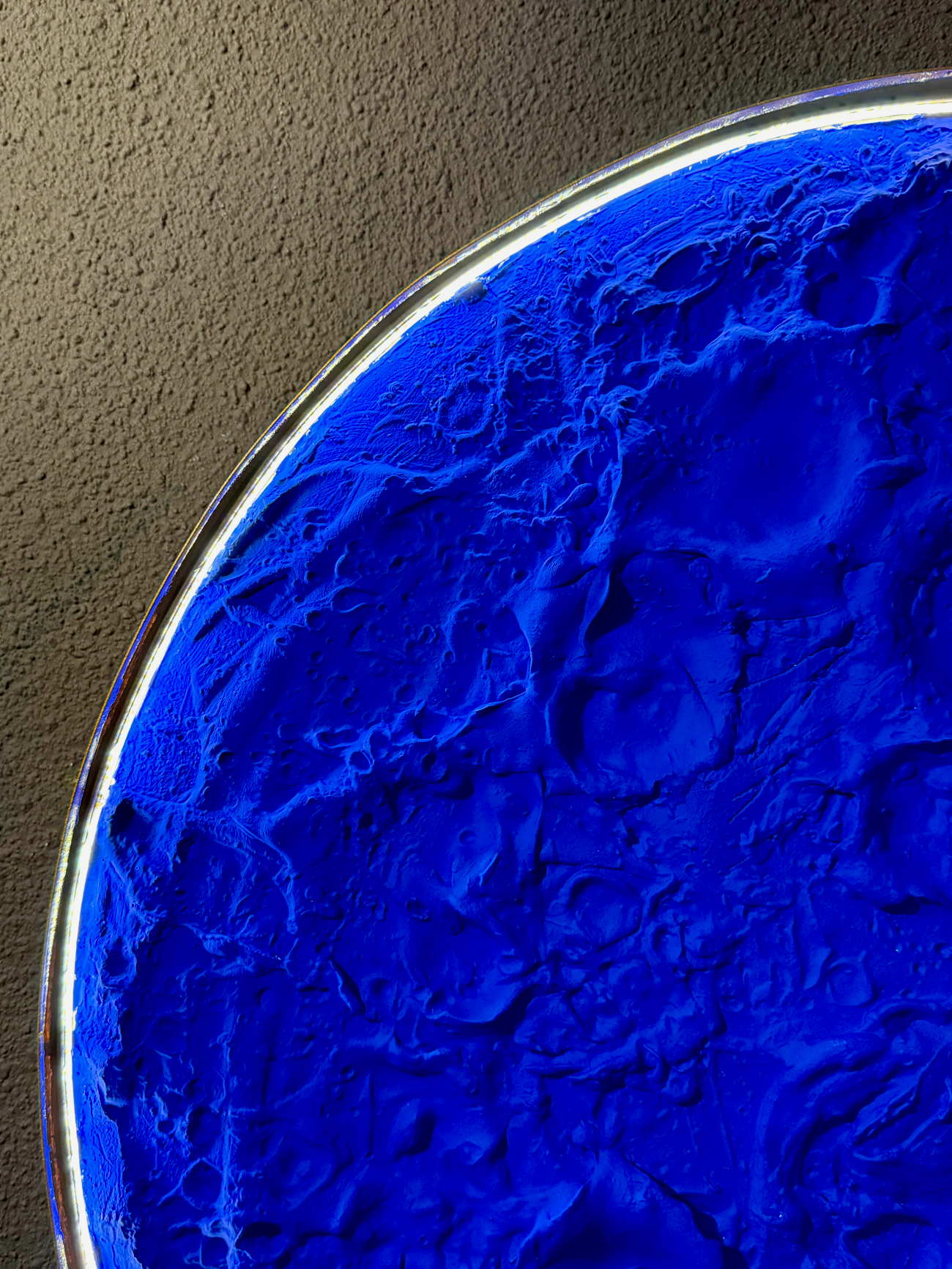 Close-up of a blue textured surface with a metallic rim on a brown background
